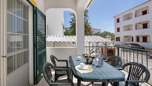 A balcony with a table and chairs, a potted plant, and a view of a building with balconies. - Apartment 'Dunamar' with Private Terrace, Wi-Fi and Air Conditioning (Castro Marim)