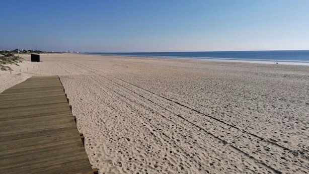 A wide sandy beach with a wooden boardwalk leading to a small structure. - Apartment 'Dunamar' with Private Terrace, Wi-Fi and Air Conditioning (Castro Marim)