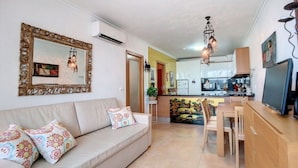A living room with a sofa, a dining table, and a kitchen in the background. - Apartment 'Athena' with Balcony, Wi-Fi and Air Conditioning (Monte Gordo)