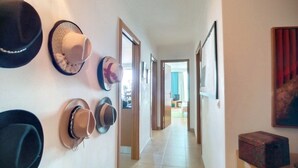 A hallway with hats on the wall, a wooden door, and a view into a room with a TV. - Apartment 'Athena' with Balcony, Wi-Fi and Air Conditioning (Monte Gordo)