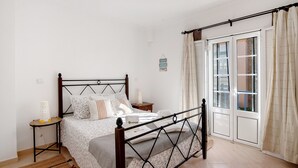 Un dormitorio con cama, mesita de noche y vistas a través de una puerta.