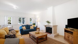 Una sala de estar con sofá, mesa de centro, chimenea, televisión y un comedor con mesa y sillas.