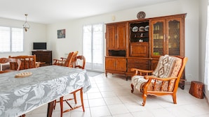 A dining area with a table, chairs, a cabinet, and a television. - Holiday Home 'Lumineuse Près La Rémigeasse' with Private Terrace, Private Garden and Wi-Fi (Dolus-d'Oléron)