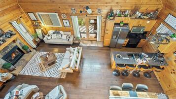 A spacious log cabin with a living area, dining space, kitchen, and a fireplace.