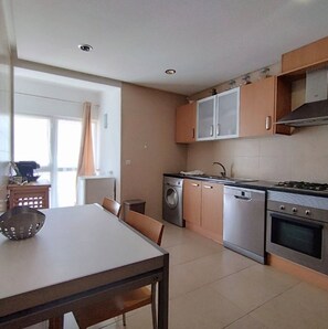 A modern kitchen with stainless steel appliances, wooden cabinets, and a dining area with a table and chairs.