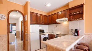 Una cocina con armarios de madera, lavadora, cafetera y encimera de mármol.
