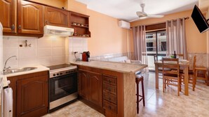 Una cocina con armarios de madera, una estufa y un comedor con una mesa y sillas.