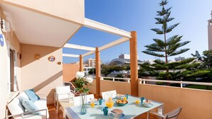 Een balkon met een ontbijttafel, wit meubilair en uitzicht op de stad.