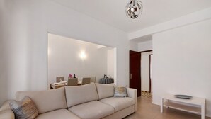 Un salón con un sofá, una mesita, una lámpara y una puerta que da a otra habitación.