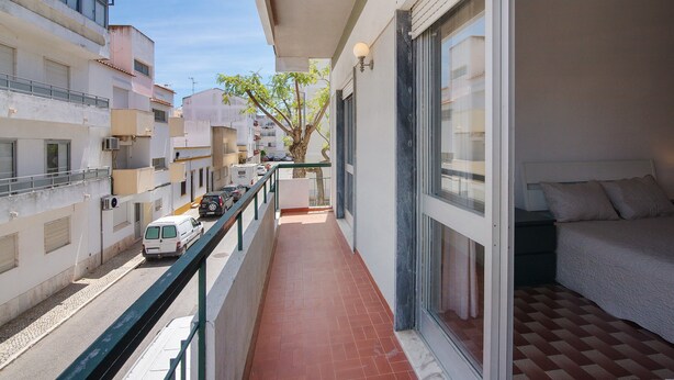Un balcón con cama, ventana y barandilla.