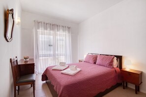 Une chambre d’hôtel comprenant un lit, un bureau, une chaise, une table de chevet et un miroir.
