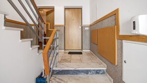 Eine Treppe mit Holzgeländer, einer Tür am oberen Ende und einer weißen Wand mit einem kleinen Fenster.