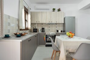 A modern kitchen with wooden cabinets, a built-in oven, a refrigerator, and a dining area with a table set for two.