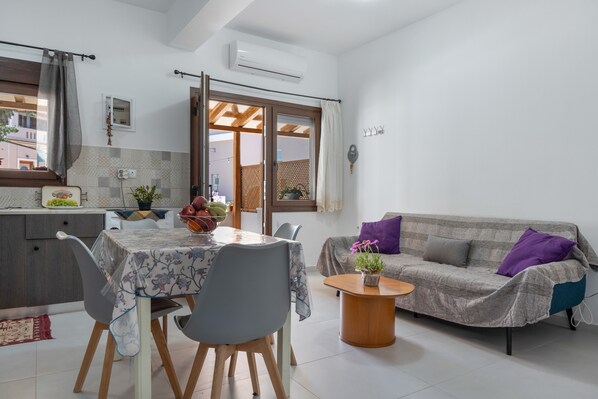 A modern kitchen with a dining table, chairs, and a sofa in a living area.