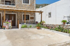 A stone building with a wooden porch, potted plants, and a clear sky.