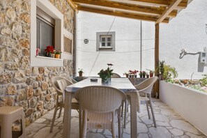 Un patio al aire libre con paredes de piedra, mobiliario de mimbre, una mesa y plantas en macetas.
