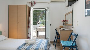 Quarto com duas camas, uma escrivaninha, uma cadeira, um guarda-roupa e janela com vista para o exterior.