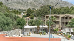 Um hotel com paredes de pedra, várias varandas e montanhas ao fundo.