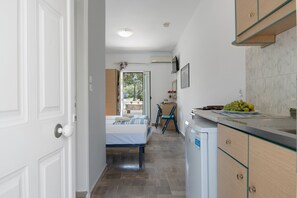 A hotel room with a bed, a desk, a chair, and a kitchenette.