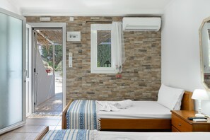 A bedroom with a bed, a nightstand, a window, and an air conditioning unit. - Apartment 'Studio 8' with Mountain View, Wi-Fi and Air Conditioning (Panormos Kalymnos)