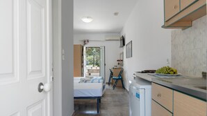 A hotel room with a bed, a desk, a chair, and a kitchenette. - Apartment 'Studio 1' with Mountain View, Wi-Fi and Air Conditioning (Panormos Kalymnos)
