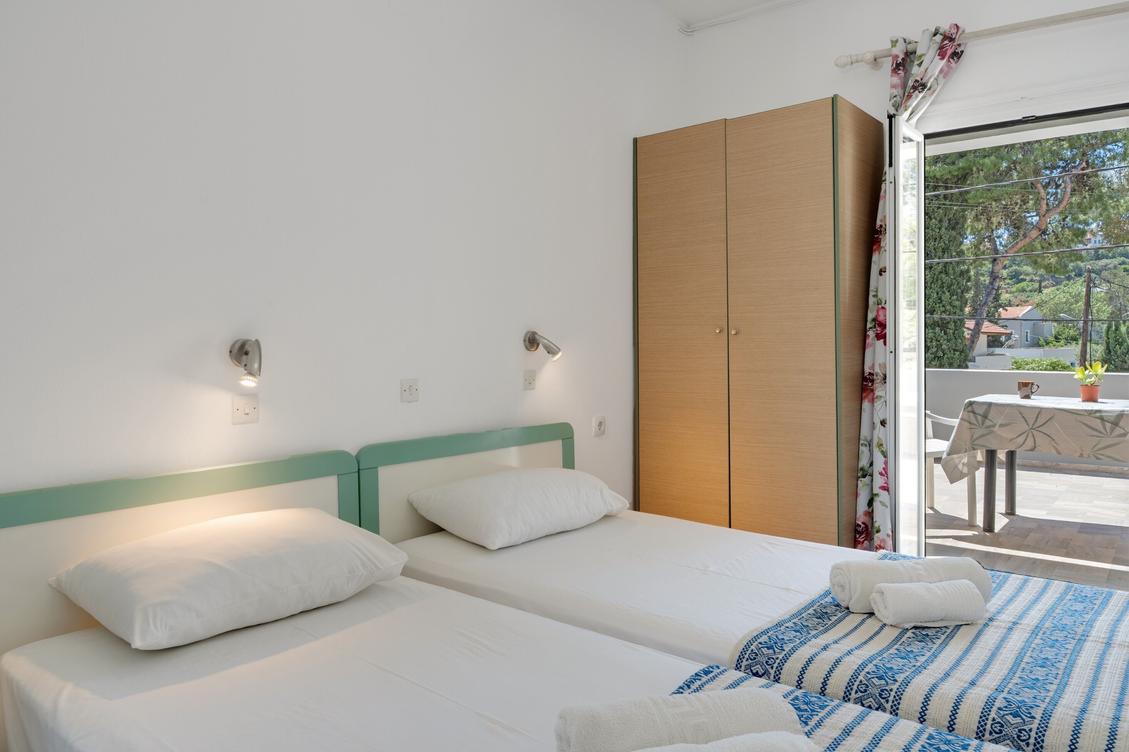 Une chambre avec deux lits, une armoire, une table et une vue par la fenêtre.