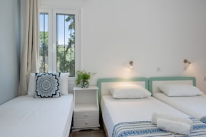 Un dormitorio con dos camas, una mesita de noche con una planta y una ventana con cortinas.