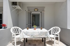 Een balkon met een tafel, stoelen, een plant in pot en uitzicht op het gebouw.
