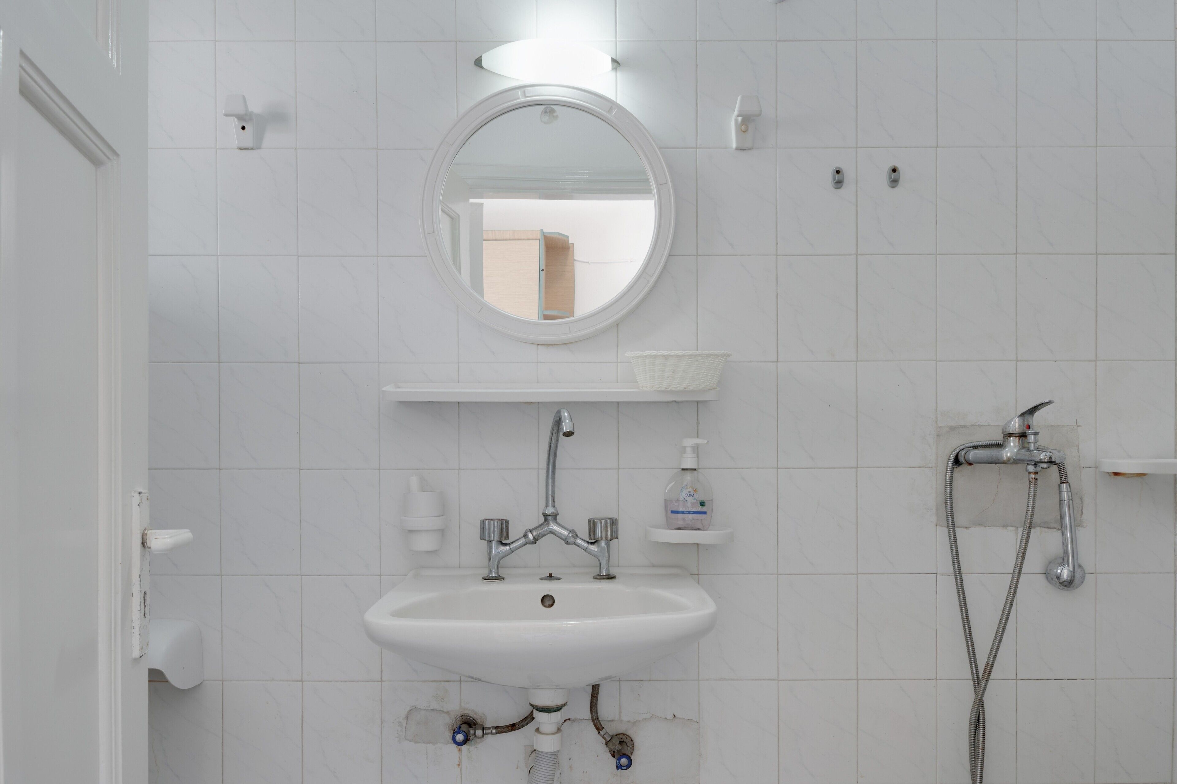 Un bagno con un lavandino bianco, uno specchio rotondo e una doccia.