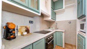 A kitchen with teal cabinets, a coffee maker, a microwave, and a stove.