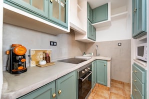 Una cocina con gabinetes verde azulado, una cafetera, un microondas y una estufa.