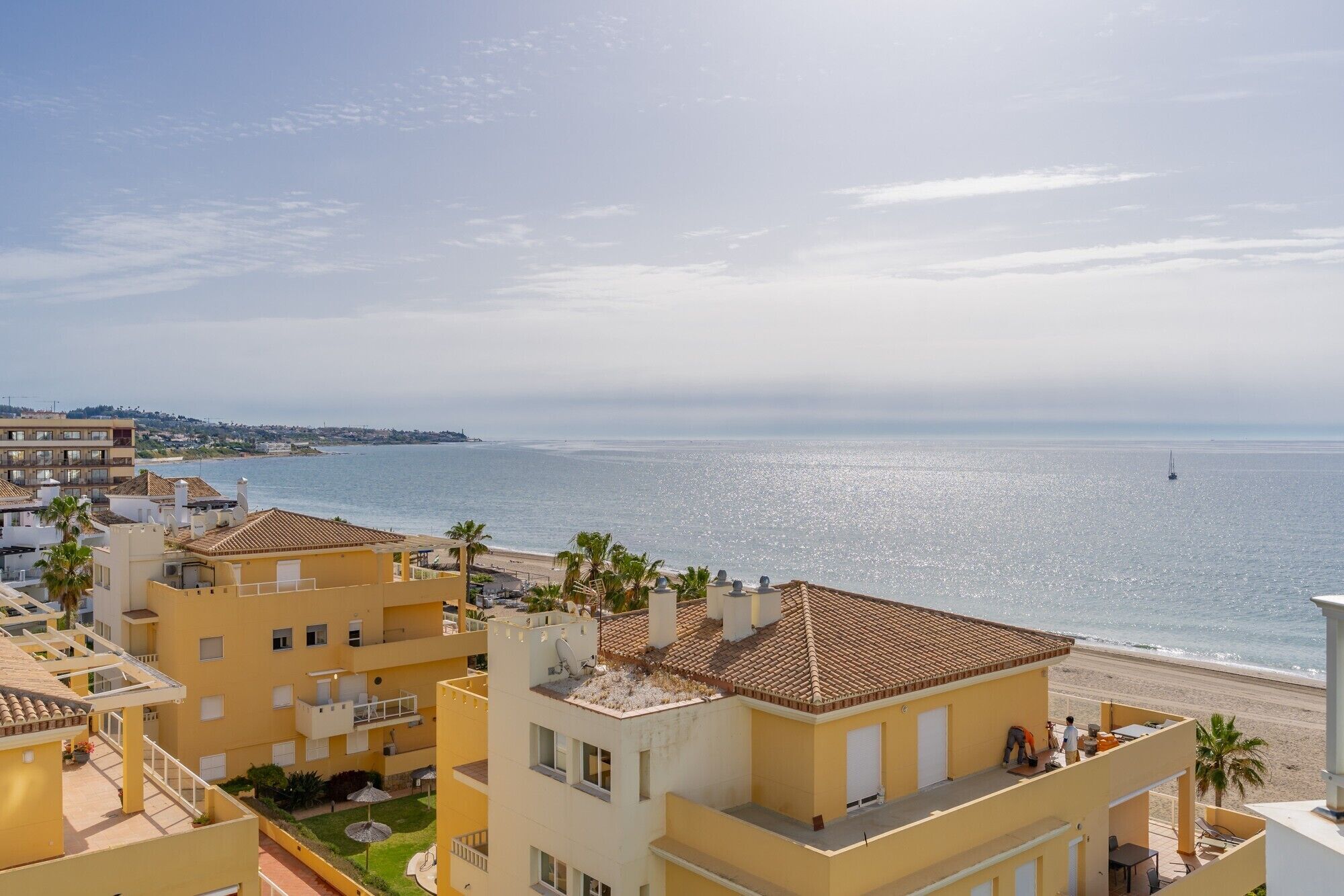 Zona residencial costera con edificios, una playa y cielo despejado.