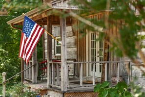 A rustic wooden house with a porch, a flag, and a welcome sign. - The Retreat at Pilot Knob | Pvt Pool | Lakeview (Gallatin)