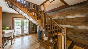 A wooden staircase with a view of a dining area and a door leading outside.