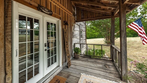 A wooden cabin with a porch, a welcome sign, and an American flag.