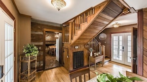 A wooden staircase with a glass door at the top, leading to a dining area with a table and chairs.