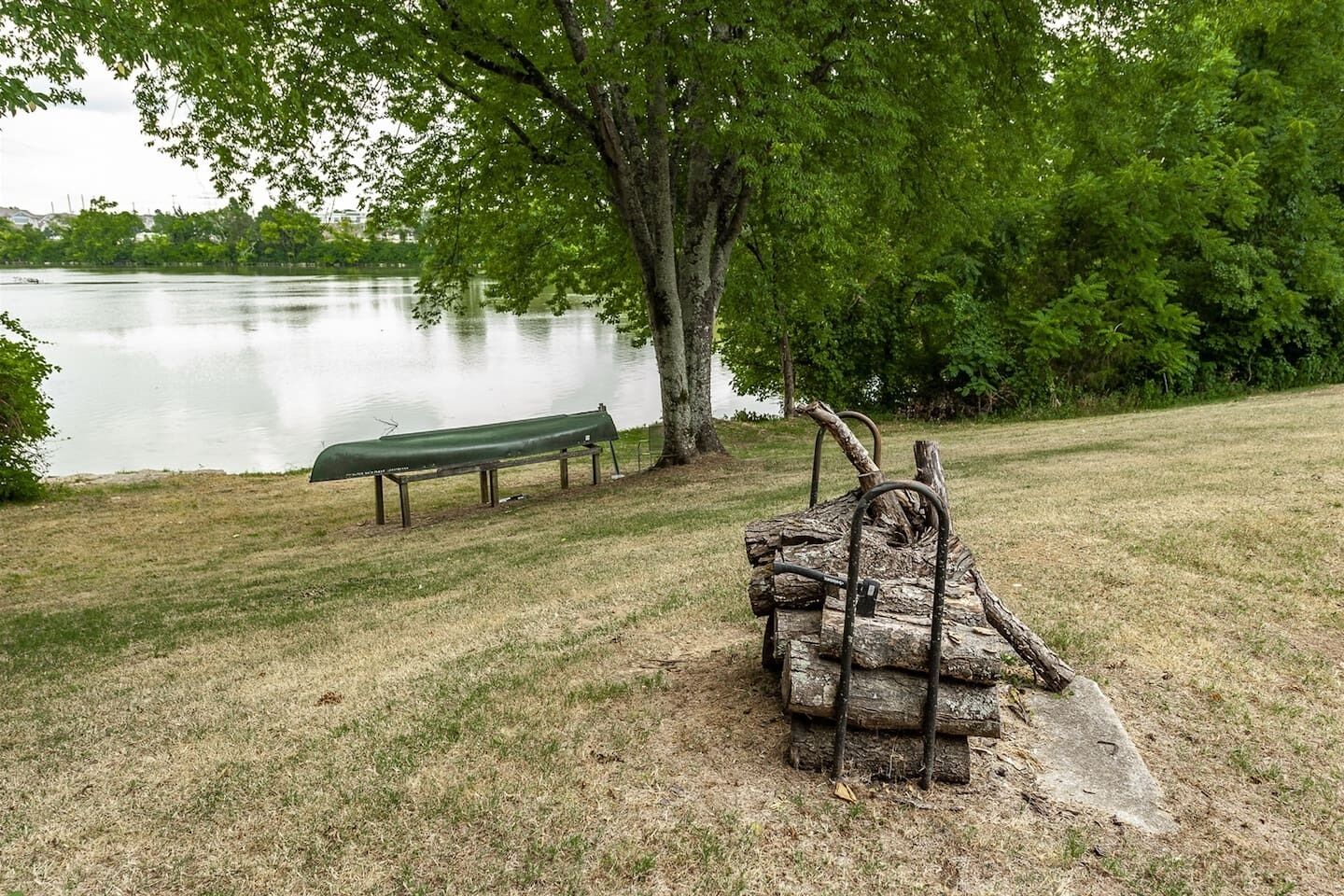 A park with a bench and a rustic wooden structure near a lake.