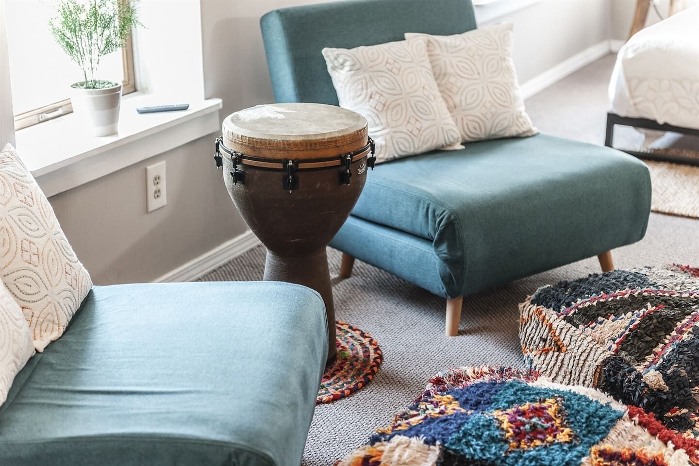 A room with a blue sofa, a drum, and a patterned rug.