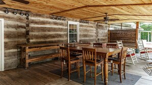 A rustic wooden cabin with a dining area featuring a large wooden table and benches.