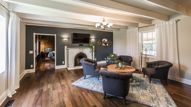 A spacious living room with a fireplace, dark wood flooring, and a large TV mounted on the wall.