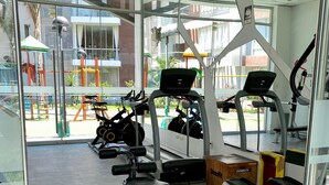 Ett gym med löpband, en bänkpress och en roddmaskin.