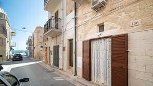 A narrow street with stone buildings, closed shutters, and a clear sky. - WePuglia - Donna Simona (Polignano a Mare)