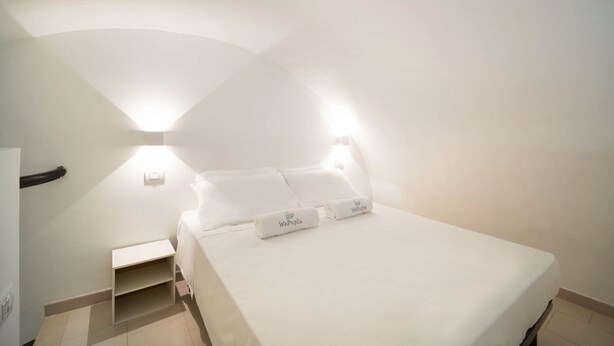 A bedroom with a bed, two bedside tables, and two wall-mounted lights. - WePuglia - Donna Simona (Polignano a Mare)