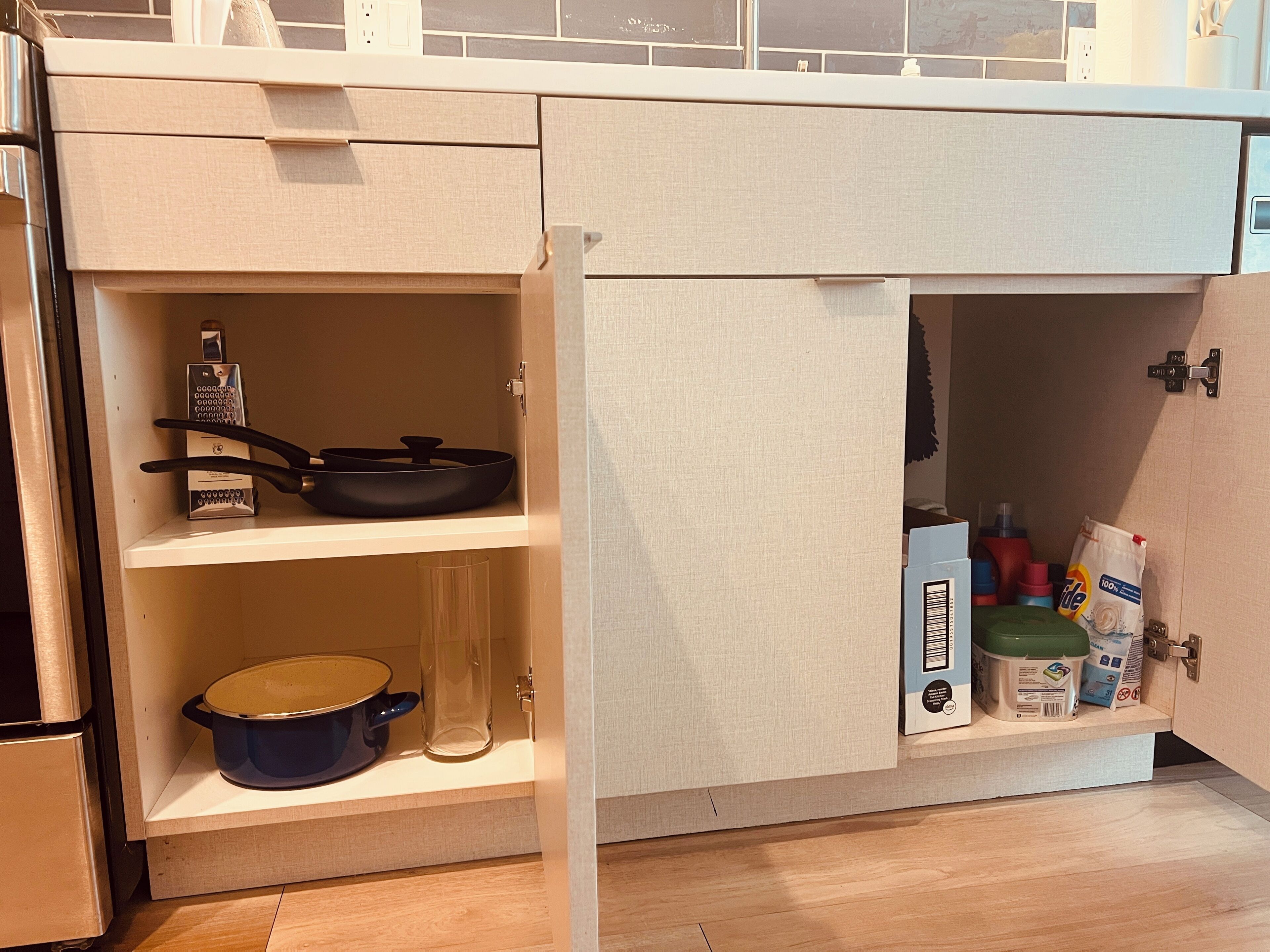 A kitchen with a built-in oven, a stove, and a sink. There are cabinets with various kitchen items and a countertop.
