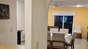 A modern living room with a dining area, featuring a kitchen counter, dining table, and chairs.