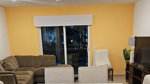 A dining area with a table set for four, surrounded by sofas and a TV stand.