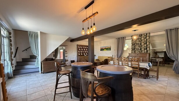 A spacious interior with a bar area, seating, and a staircase.
