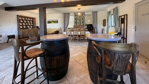 A kitchen with a bar area, wooden stools, and a large barrel.