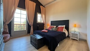 A bedroom with a bed, bedside tables, curtains, a window, and a suitcase.