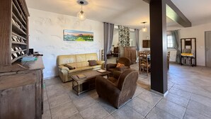 A spacious living area with a sofa, armchair, and a dining table.